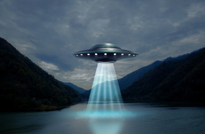 Alien spaceship, UFO, emitting light beam in air over lake