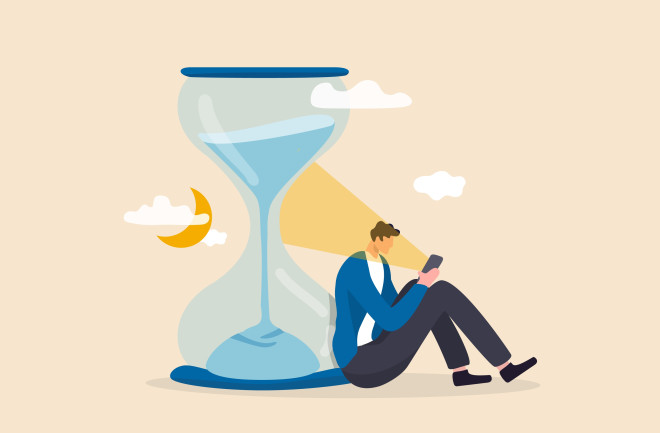 Brain and time: Exhausted man sitting with sandglass using smartphone with bright light on his face.