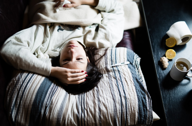 sick brunette woman lying in bed with flu