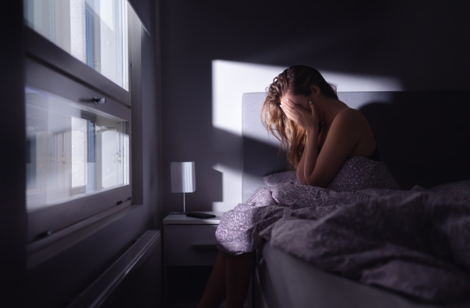 woman with anxiety sitting in bed head in hands