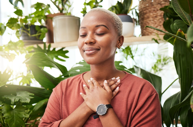Balance, breathing and young woman by plants for zen meditation in a greenery nursery. Breathe, gratitude and young African female person with a relaxing peace mindset by an indoor greenhouse garden.